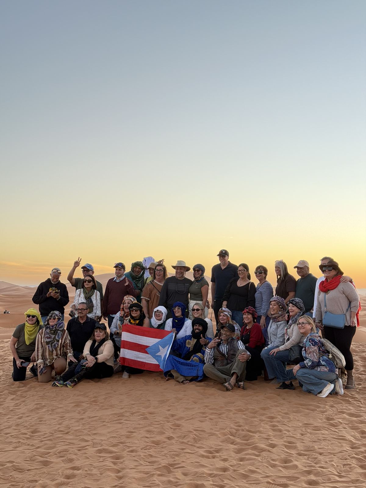 Grupo de viajeros latinoamericanos en las dunas al atardecer